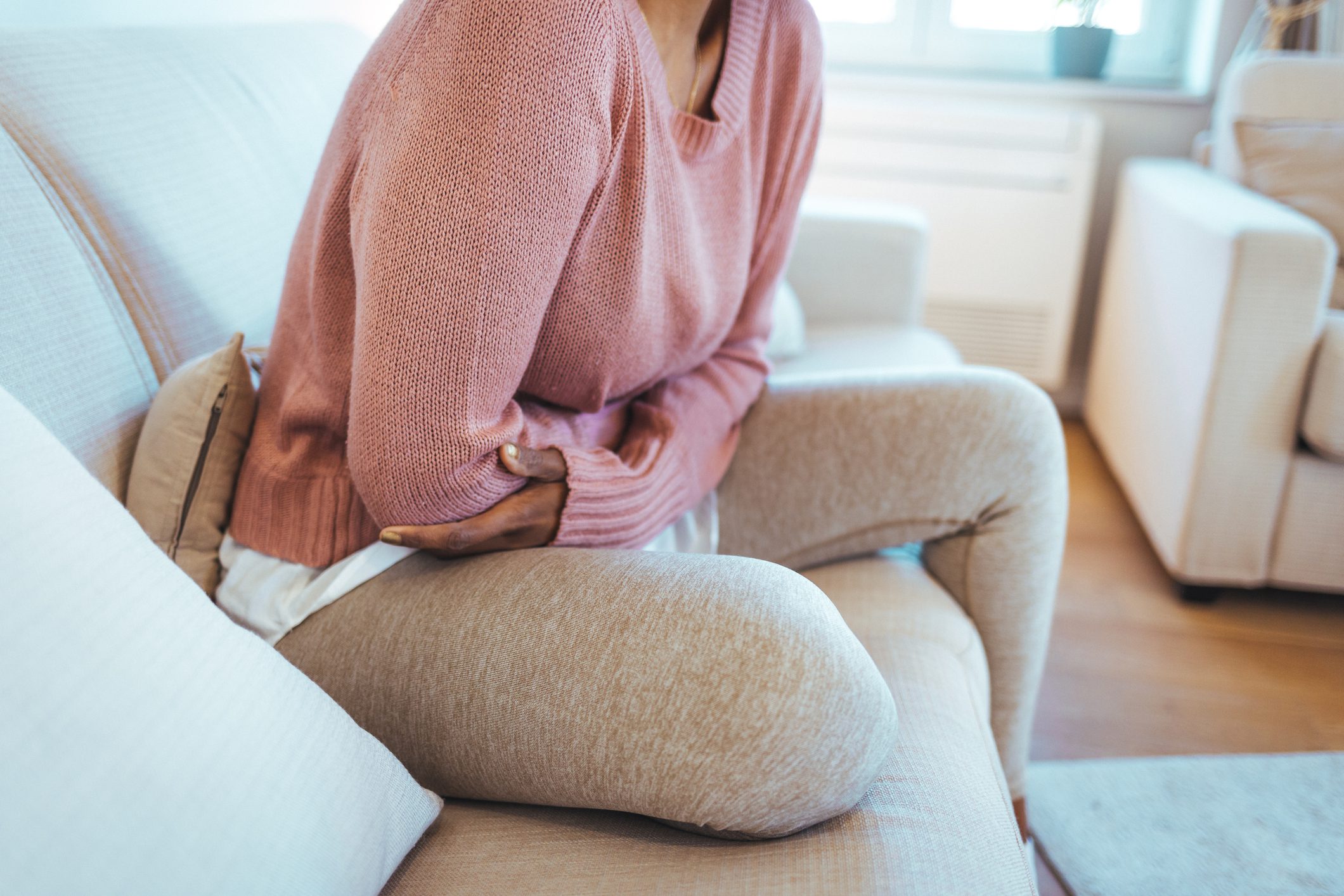 Person sitting, holding stomach in discomfort.