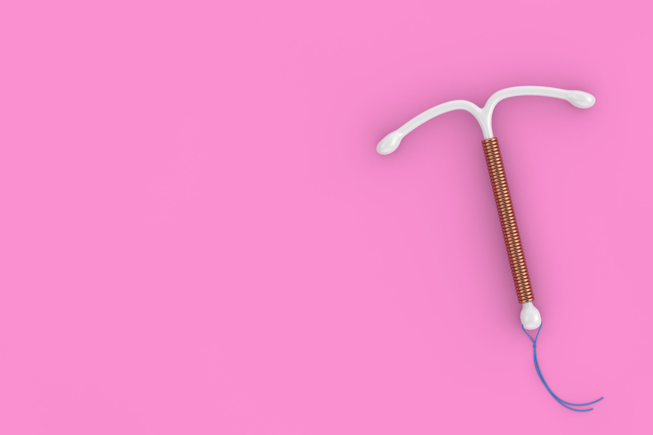 Copper IUD on a pink background.