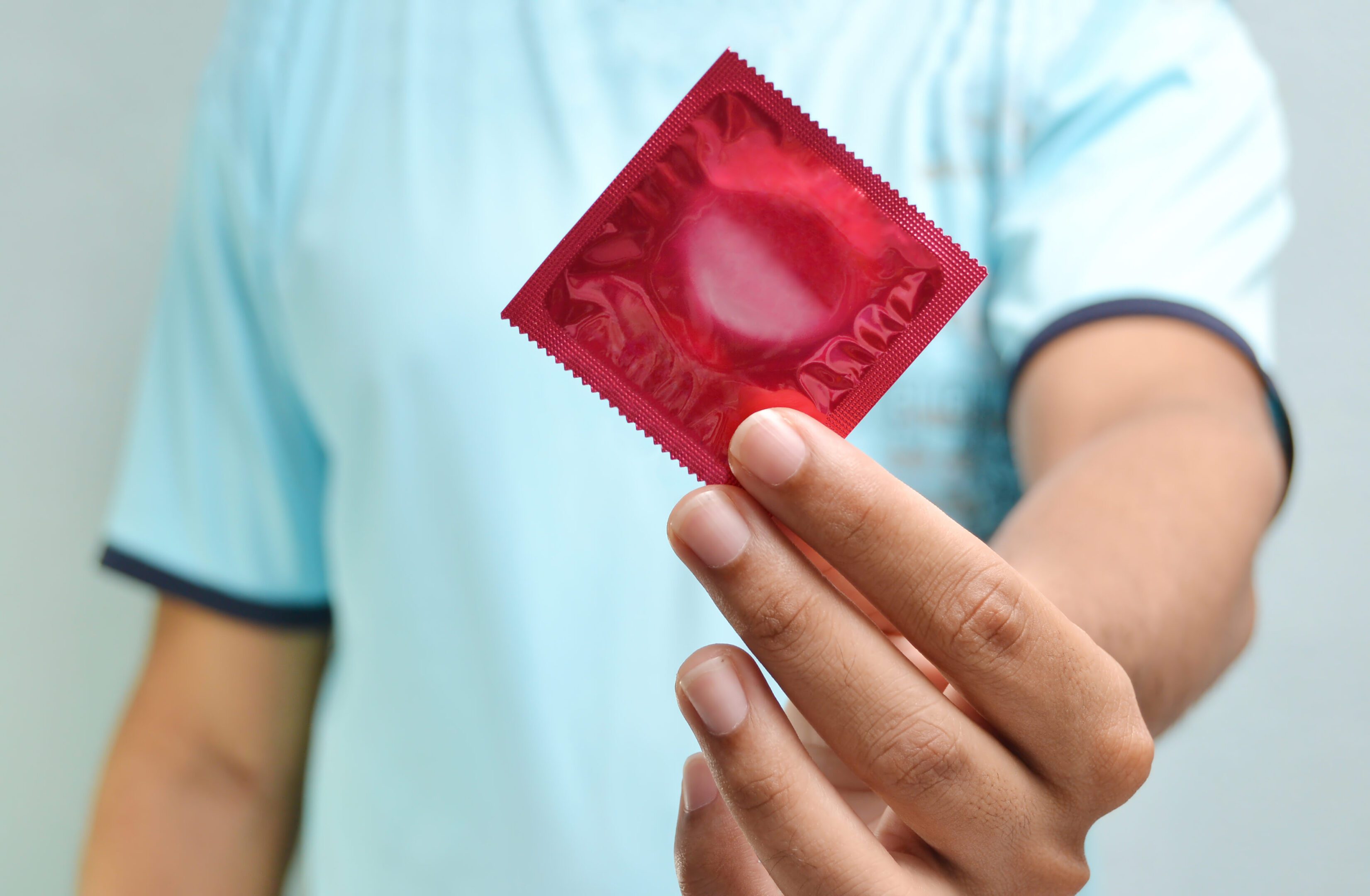 Hand holding a red condom package.