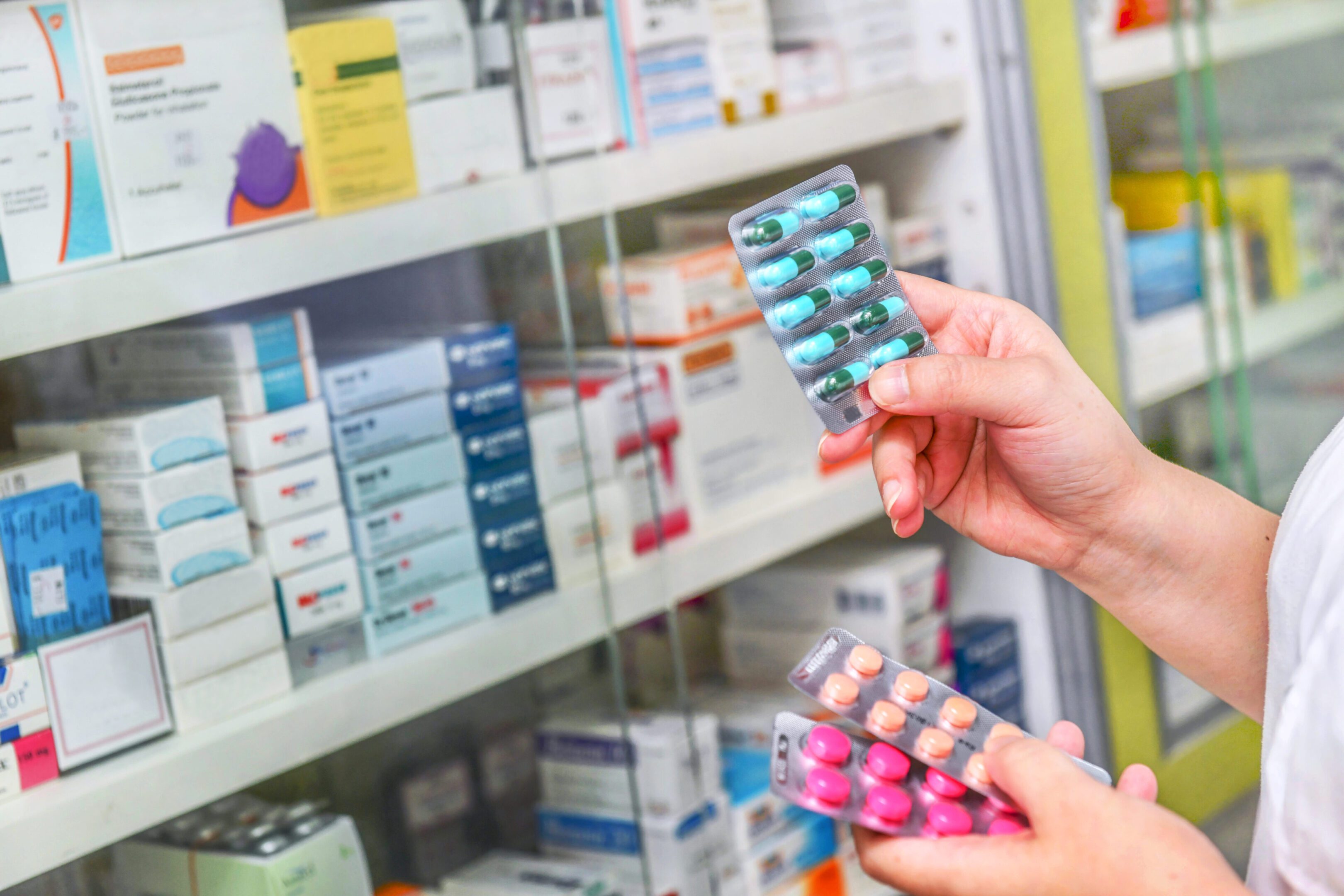 Person holding blister packs in pharmacy.