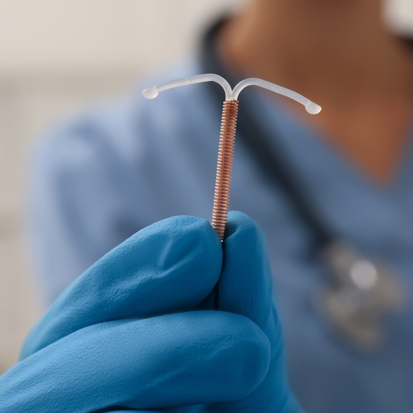 Gloved hand holding a copper IUD device.
