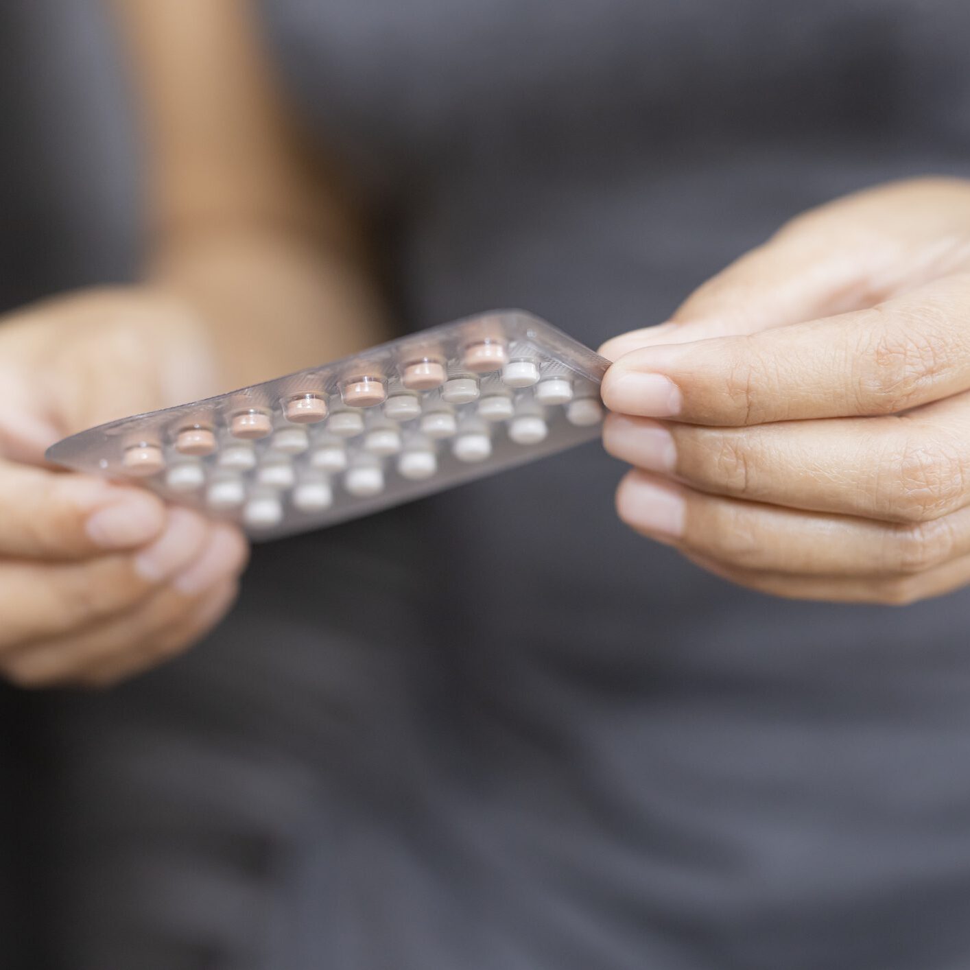 Hands holding a blister pack of pills.